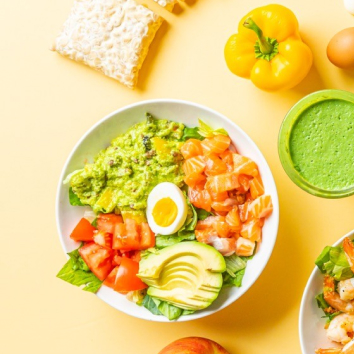 흰색 그릇에 연어, 아보카도, 토마토, 계란 등이 담겨 있습니다.