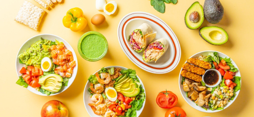 다양한 샐러드와 랩, 과일, 채소가 노란 배경에 놓여 있습니다.